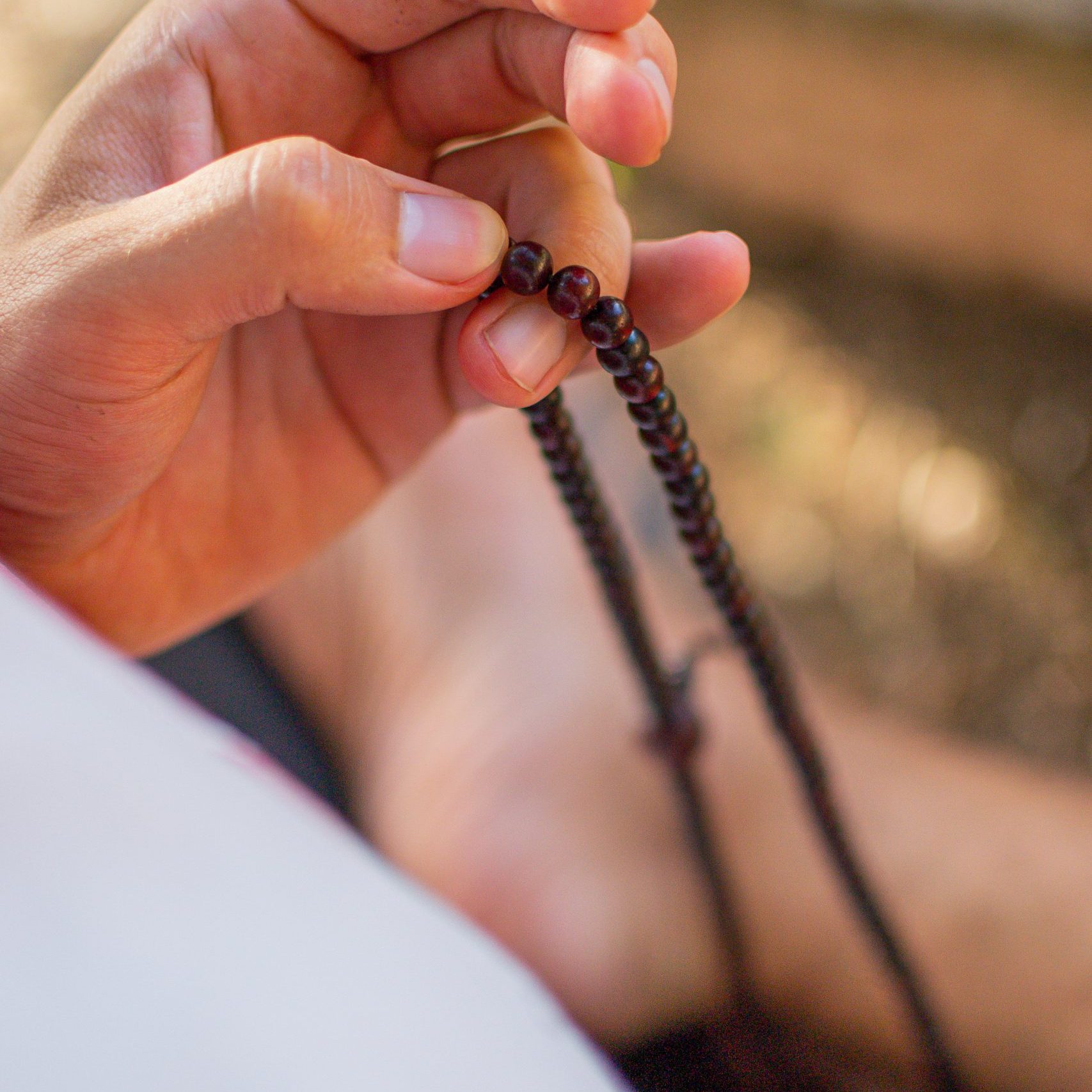 mano y collar de bolitas mantras